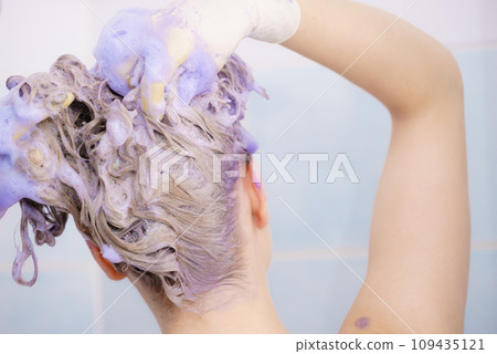 Woman applying toner shampoo on her hair Woman applying toner shampoo on her hair 109435121