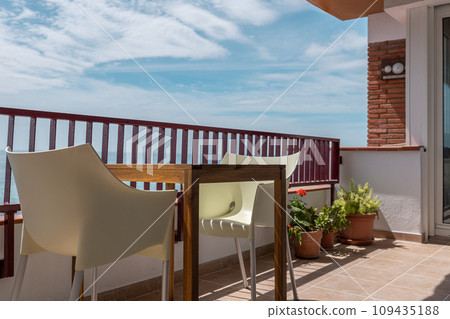 Wooden table with cozy armchairs on sunny hotel balcony Wooden table with cozy armchairs on sunny hotel balcony 109435188