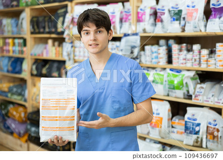Smiling young veterinarian offering package of healthy dry pet food 109436697
