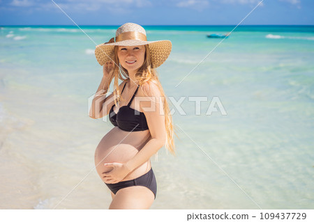 Radiant and expecting, a pregnant woman stands on a pristine snow-white tropical beach, celebrating the miracle of life against a backdrop of natural beauty Radiant and expecting, a pregnant woman stands on a pristine snow-white tropical beach, celebrating the miracle of life against a backdrop of natural beauty 109437729