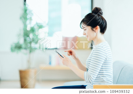 在客廳裡操作智能手機的年輕女子。 109439332