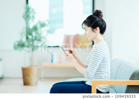 在客廳裡操作智能手機的年輕女子。 109439333