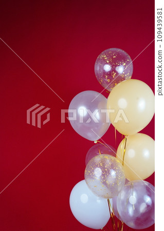 Vertical photo of white and transparent balloons on red burgundy background. Space for text 109439581