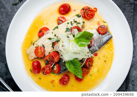 unpeeled fish with gravy, herbs, cherry tomatoes and onions, top view 109439698