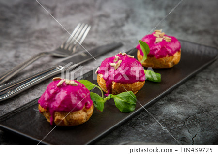 dessert of baked buns with raspberry topping and seed decorations, side view 109439725