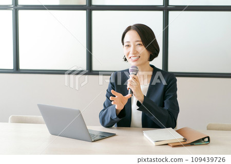 A woman in a suit speaking with a microphone 109439726
