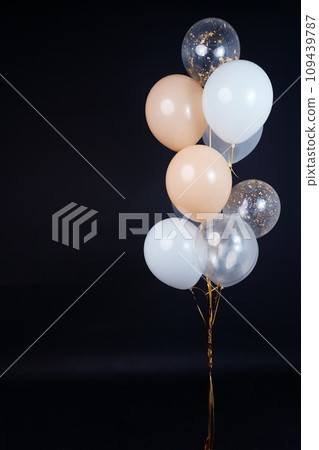 A bunch of balloons in white, beige and transparent colors on a dark background with space for an inscription 109439787
