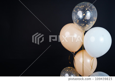 Bunch of balloons of white, beige and transparent colors on a dark background. Place for the inscription 109439815