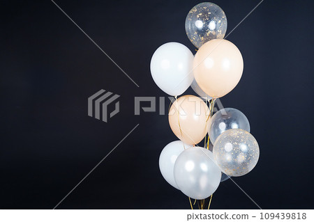 On a black background, balloons of light shades - white, beige, transparent - are flying. Space for text On a black background, balloons of light shades - white, beige, transparent - are flying. Space for text 109439818