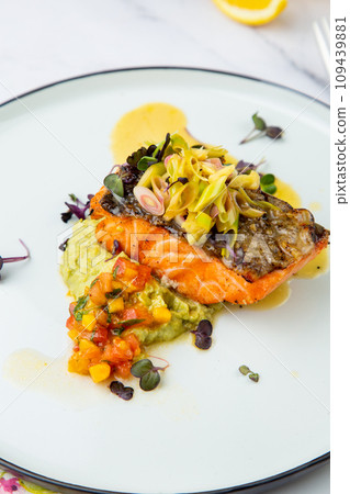 red fish with vegetable sauce and puree on a round plate side view 109439881
