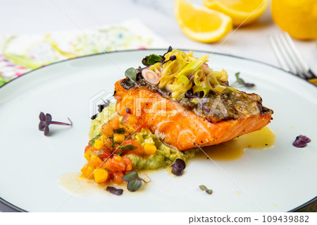 red fish with vegetable sauce and puree on a round plate side view 109439882