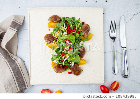 meat medallions with arugula, peach slices and red berries, side view 109439985
