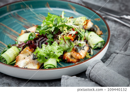 salad with arugula, lettuce, cucumber rolls, fish and sesame seeds, top view 109440132
