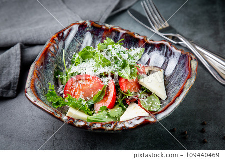 salad with herbs, tomatoes, grated cheese, sesame seeds and pieces of cheese, top view 109440469
