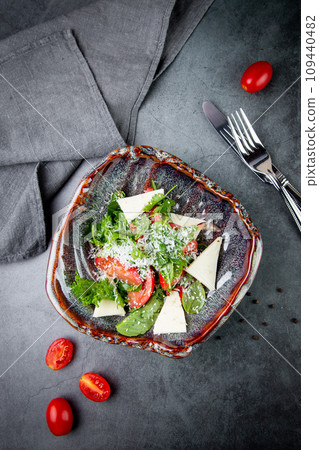 salad with herbs, tomatoes, grated cheese, sesame seeds and pieces of cheese, top view 109440482