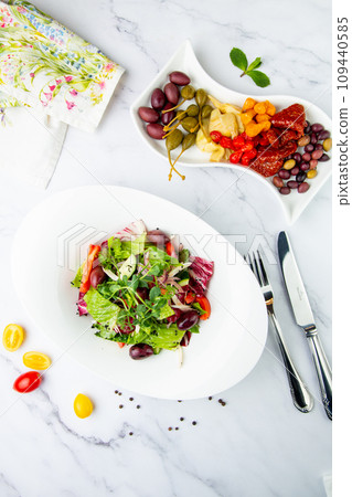 salad of greens, lettuce leaves, cucumbers, pink onions, side view 109440585