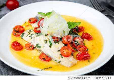 unpeeled fish with gravy, herbs, cherry tomatoes and onions, top view 109440711