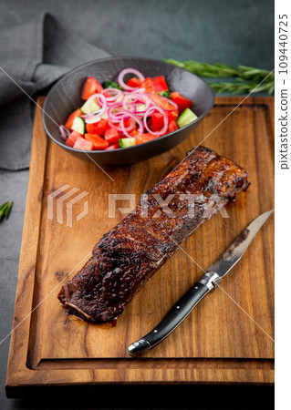 well-done steak with tomato and cucumber salad on a wooden tray, side view well-done steak with tomato and cucumber salad on a wooden tray, side view 109440725
