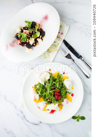 arugula salad with peach slices and red berries on a white plate top view arugula salad with peach slices and red berries on a white plate top view 109440726