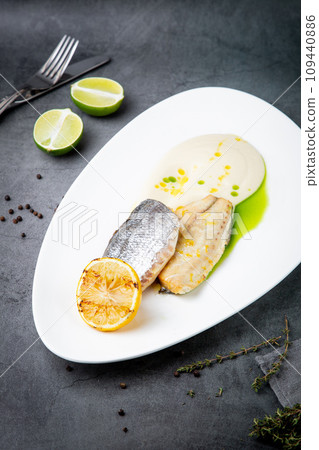pieces of fried fish with sauce and fried lemon on a white plate side view 109440886