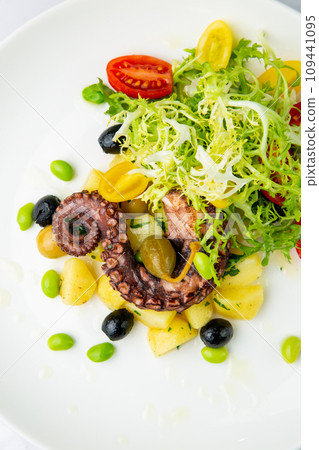 salad with olives, herbs, cherry tomatoes, potatoes and octopus tentacles top view salad with olives, herbs, cherry tomatoes, potatoes and octopus tentacles top view 109441095