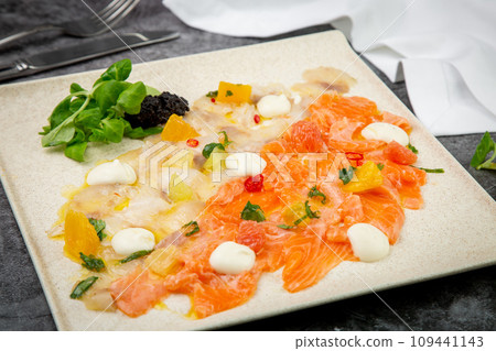 sliced red and white fish with mozzarella cheese and herbs, top view 109441143