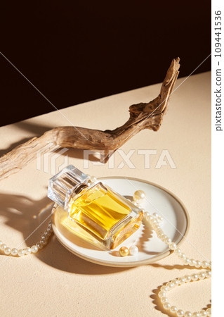 Bottles of cosmetic essential oil on round ceramic dish with pearls and dry twig decorated on black and beige background. Mockup bottle for design packaging. Concept for perfume product Bottles of cosmetic essential oil on round ceramic dish with pearls and dry twig decorated on black and beige background. Mockup bottle for design packaging. Concept for perfume product 109441536