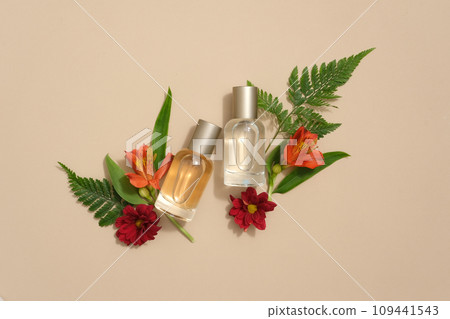 Aroma bottle of essential oil with fresh beautiful flowers & leaves decorated on beige background. Top view, mockup for design. Herbal aromatherapy product 109441543