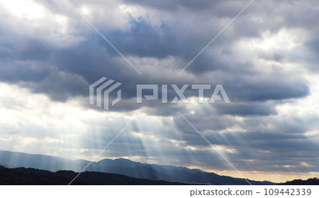 A veil of light shining into the mountains from between the clouds 109442339