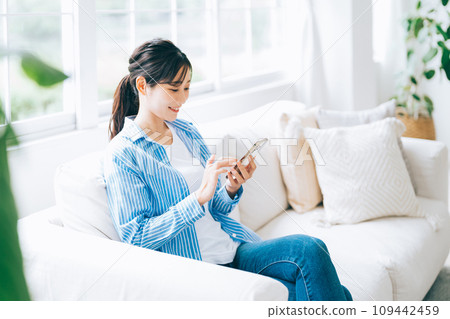 坐長沙發和操作智能手機的婦女 109442459