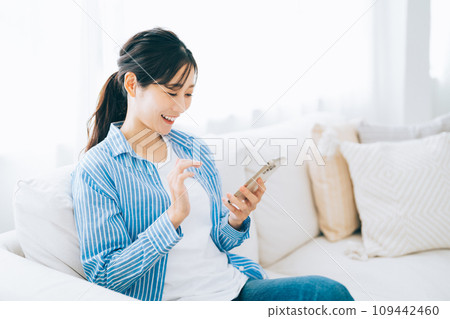 坐長沙發和操作智能手機的婦女 109442460