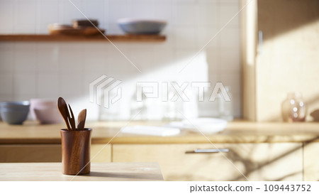 A sunny kitchen with white tile walls, a wooden table and sink. 109443752