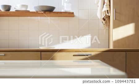 A sunny kitchen with white tile walls, a wooden table and sink. 109443781