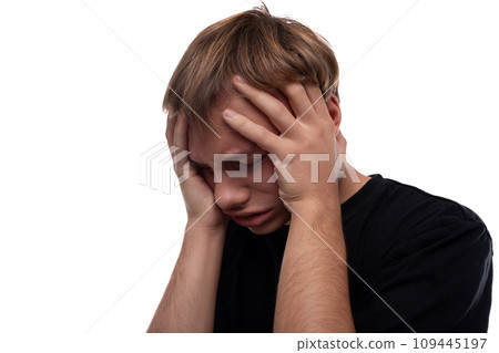 Worried young man with blond hair in a black T-shirt thinks about problems and holds his head 109445197