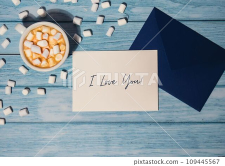 I LOVE YOU text on valentine card inscription positive quote phrase Greeting card blue envelope with white cup of coffee and marshmallows on wooden blue background holiday I LOVE YOU text on valentine card inscription positive quote phrase Greeting card blue envelope with white cup of coffee and marshmallows on wooden blue background holiday 109445567