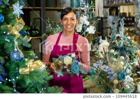 Portrait of a woman seller holding a Christmas composition with candles Portrait of a woman seller holding a Christmas composition with candles 109445618