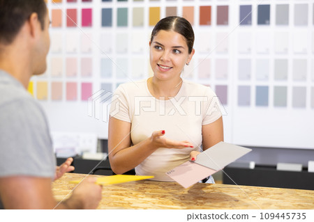 Smiling young salesgirl of painting supply store consulting customer 109445735
