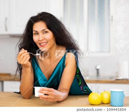 Portrait of woman eating yoghurt at home Portrait of woman eating yoghurt at home 109445804