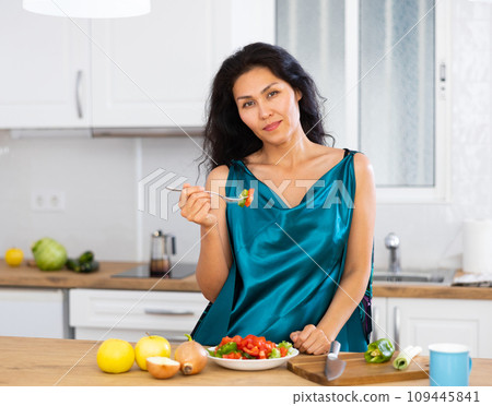 Portrait of woman eating salad at home 109445841