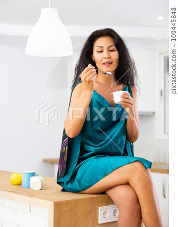 Portrait of woman eating yoghurt at home 109445848