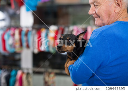 Portrait of elderly man with his doberman pinscher dog visiting pet supplies shop 109445895