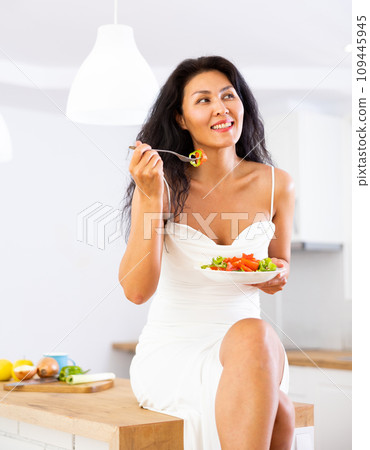 Portrait of woman eating salad at home 109445945