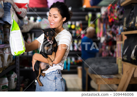 Woman choosing dog food in pet shop Woman choosing dog food in pet shop 109446006