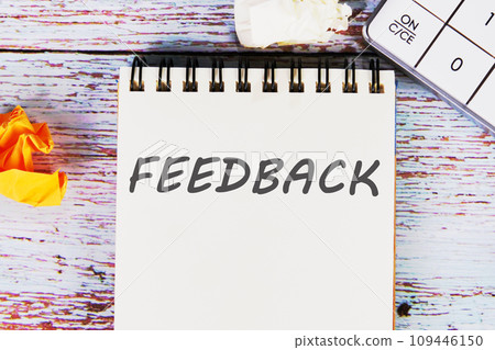 Feedback word written on a sheet of notebook lying on old vintage boards with a calculator and folded paper Feedback word written on a sheet of notebook lying on old vintage boards with a calculator and folded paper 109446150