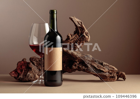 Bottle and glass of red wine with old weathered snag. 109446396