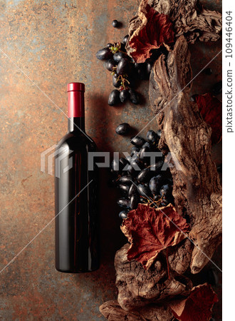 Bottle of red wine with blue grapes on a rusty background. Bottle of red wine with blue grapes on a rusty background. 109446404