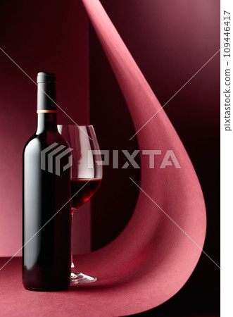 Bottle and glass of red wine on a red background. 109446417