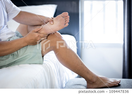 Asian middle aged man massaging his sole of the foot,suffering from Plantar fasciitis,foot pain problem,inflammation of the fascia of muscle,painful and stiffness in feet and heels,sore in ankle joint 109447836