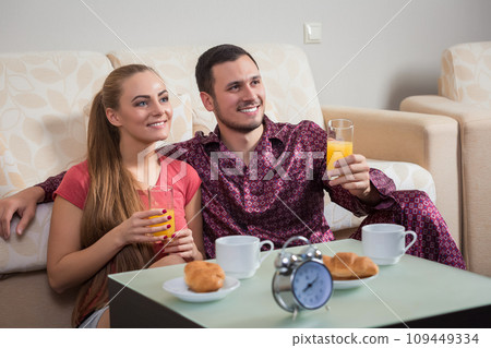 Cute young couple having breakfast, eating croissants, drinking orange juice. Cute young couple having breakfast, eating croissants, drinking orange juice. 109449334