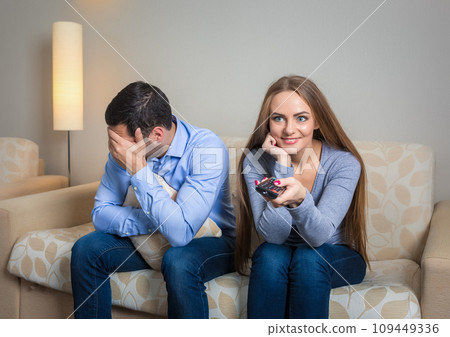 Portrait of couple sitting on sofa watching television. Portrait of couple sitting on sofa watching television. 109449336